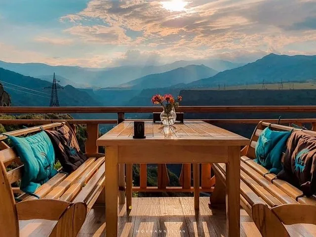 A wooden table and benches on a balcony with mountain views