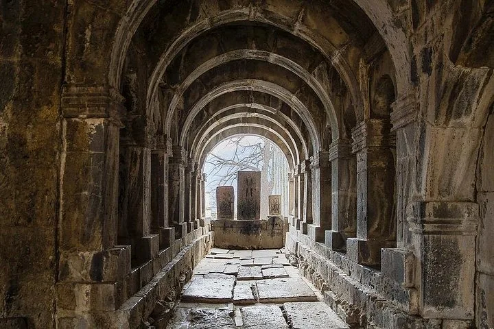 Arched stone corridor at Sanahin Monastery with carved khachkars at the end