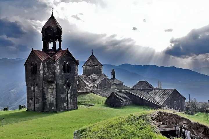 Historischer Steinkomplex eines Klosters unter dramatischem, sonnendurchflutetem Wolkenhimmel