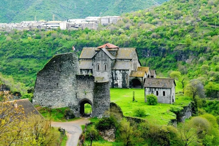 Monastero storico in pietra con mura fortificate in una valle verde